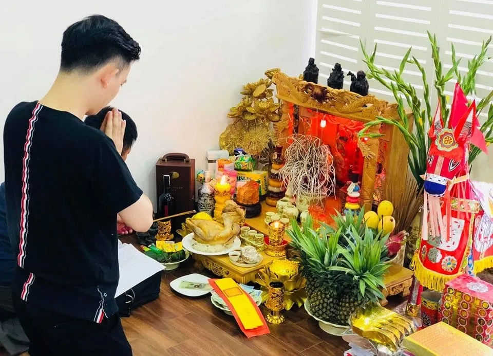 Gia chủ chắp tay khấn trước bàn thờ Thần Tài Thổ Địa với lễ vật trước khi di chuyển khi sửa nhà